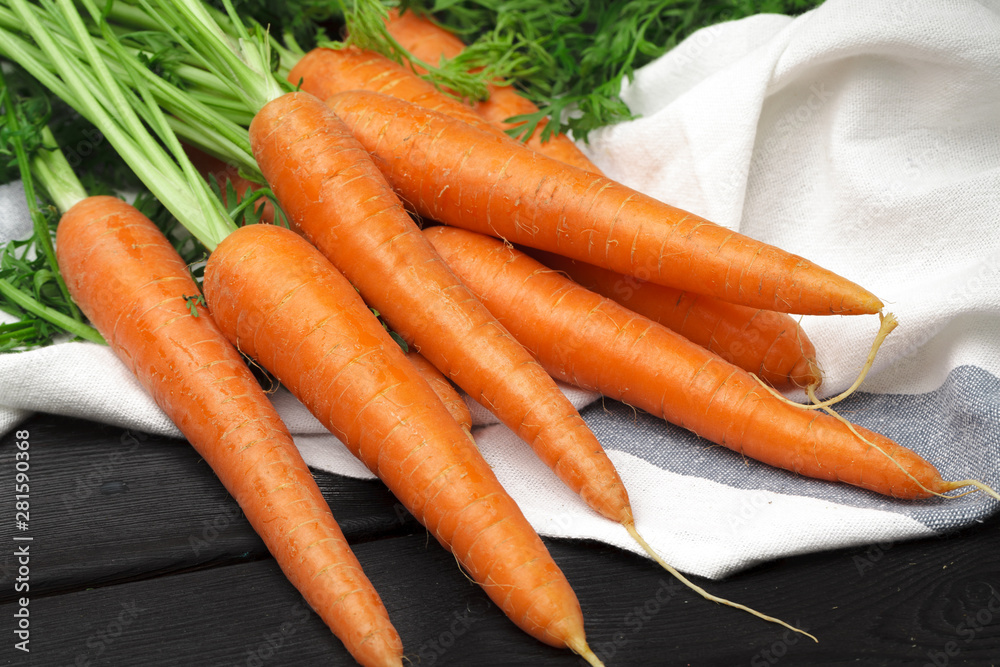 Bunch of fresh carrots with green leaves on wooden table Bunch of fresh carrots with green leaves on wooden table
