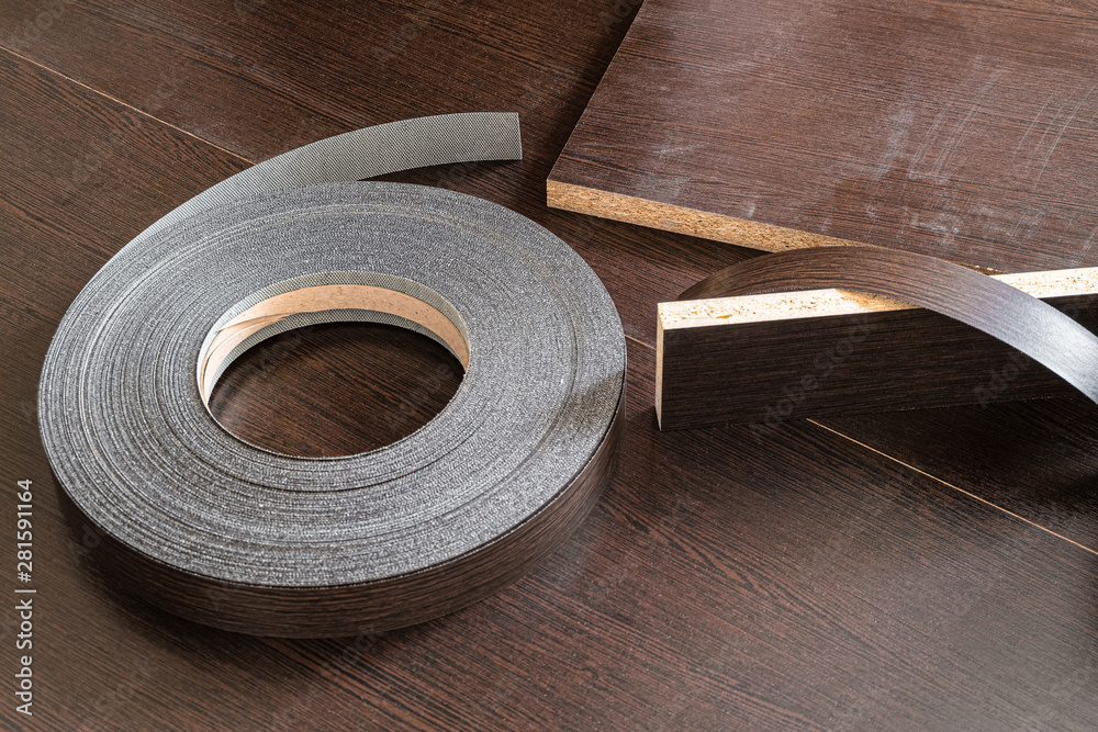 Roll melamine edge for finishing of furniture. Edging tape lying on laminated  chipboard sheets wenge color. foto de Stock | Adobe Stock