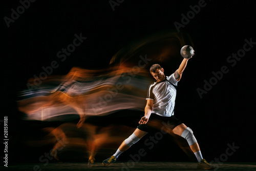 Caucasian young handball player in action and motion in mixed lights over black studio background. Fit male professional sportsman. Concept of sport, movement, energy, dynamic, healthy lifestyle. © master1305