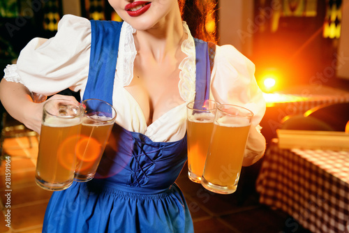 Young beautiful girl holds four glasses of beer in hands at celebration oktoberfest