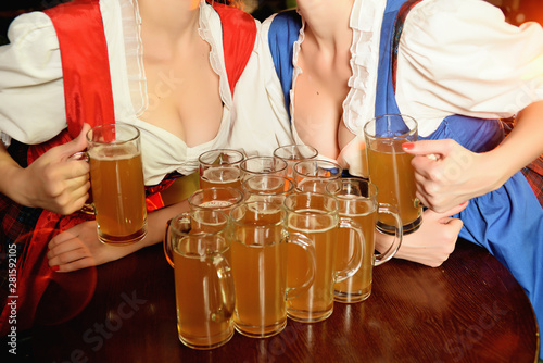 A lot of glasses of beer between the breasts of young girls on the holiday Oktoberfest