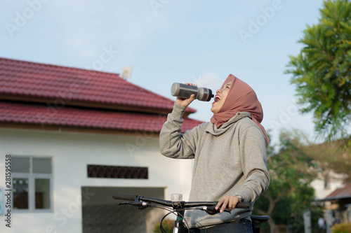 portrait of hijab woman wearing a bicycle rider wearing a bicycle and drinking water