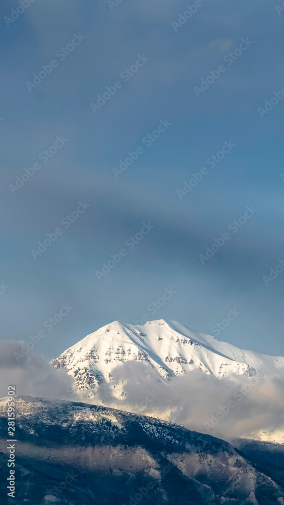 Vertical Beautiful view of a mountain with its peak covered with sunlit white snow
