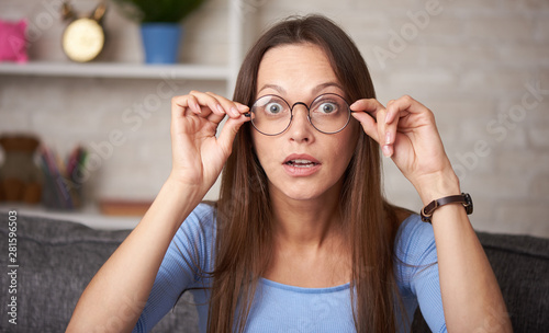 Shocked young woman in eyeglasses looking at camera