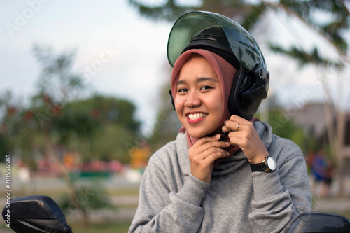 portrait of hijab  woman wearing a helmet before riding a motorcycle in a park