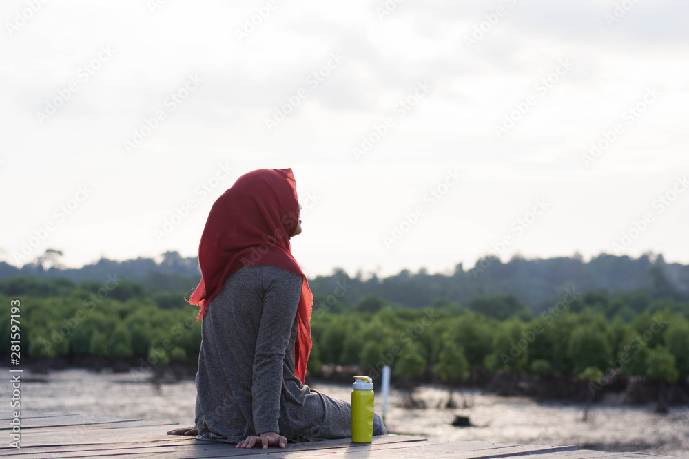 portrait of hijab woman was sitting on the boardwalk in the sunshine of a beautiful mangrove garden while waiting portrait of hijab woman was sitting on the boardwalk in the sunshine of a beautiful mangrove garden while waiting