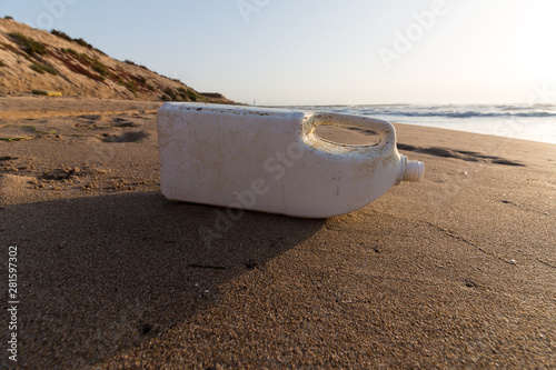 White plastic bottle abandoned on mediterranean spanish beach (Guardamar del segura), sea on background