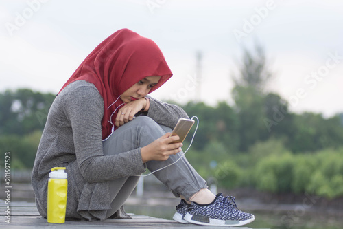 close-up shot of hjab women listening to music using a headset while sad