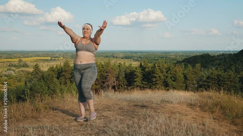 Wallpaper Mural Young plus size girl in sporty top and leggings doing sport exercises on grass spending time in highlands in the morning Torontodigital.ca