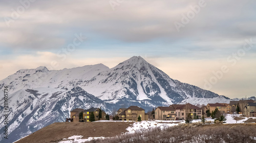 Panorama frame Homes with view of towering snow peaked mountain and overcast sky in winter