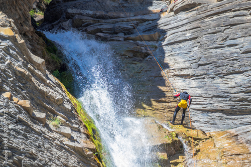 people rappelling in an impressive waterfall