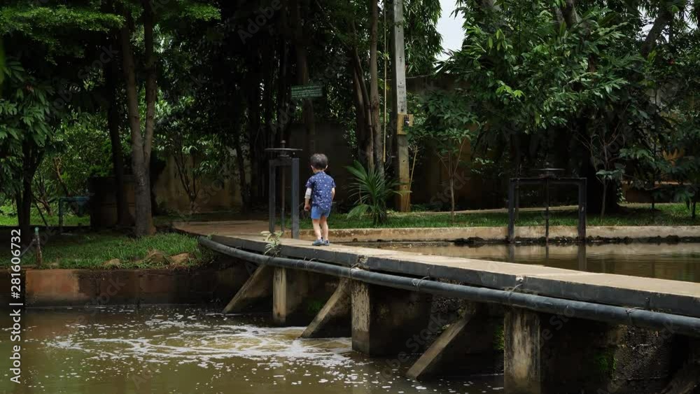 little boy walking on bridge cross small water gate in the river little boy walking on bridge cross small water gate in the river
