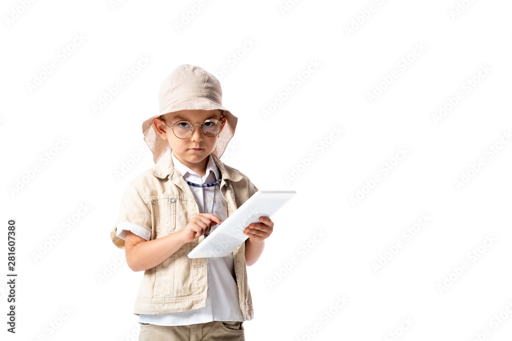 serious explorer child in glasses and hat holding digital tablet and looking at camera isolated on white serious explorer child in glasses and hat holding digital tablet and looking at camera isolated on white