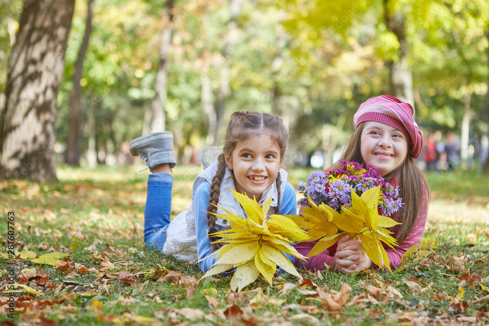 Girl with Down syndrome and little girl in autumn park. Girl with Down syndrome and little girl in autumn park.