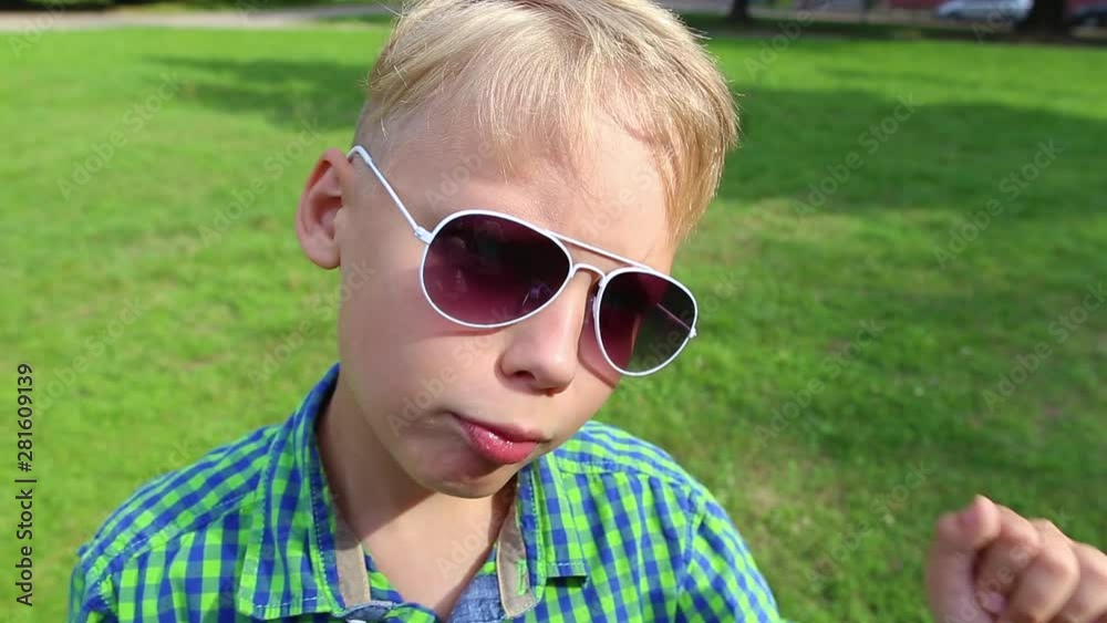 Closeup portrait of cute white kid making funny faces standing outdoor in summer green park. Real time video footage. Closeup portrait of cute white kid making funny faces standing outdoor in summer green park. Real time video footage.