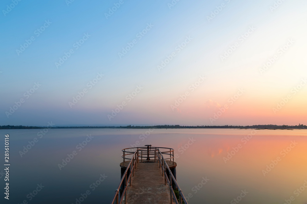 Landscape of the sunset reflaction water in the river with Floodgate in the reservoir at rural Thailand. The view of the sky reflects the water in the evening on the dam.