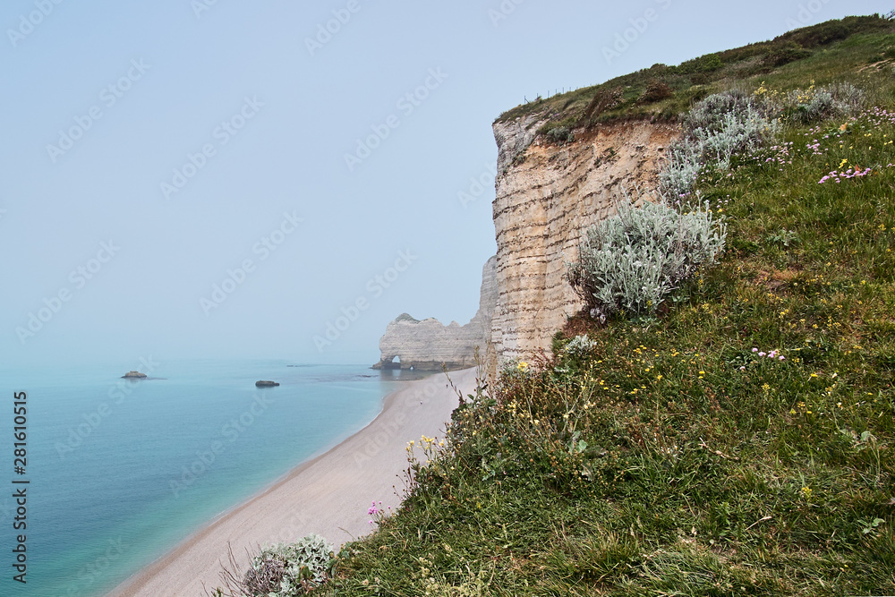 Misty morning fog at the famous natural cliffs in Etretat. Etretat is a commune in Seine-Maritime department in Haute-Normandie region in France. Etretat is now a famous French seaside resort