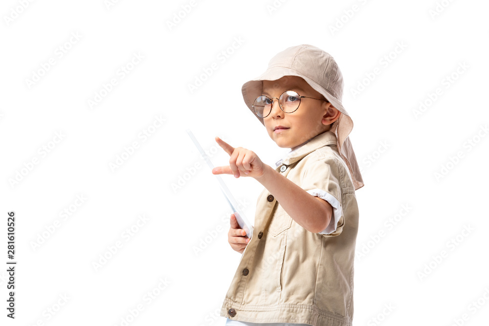 pensive explorer child in glasses and hat holding digital tablet and pointing with finger isolated on white pensive explorer child in glasses and hat holding digital tablet and pointing with finger isolated on white