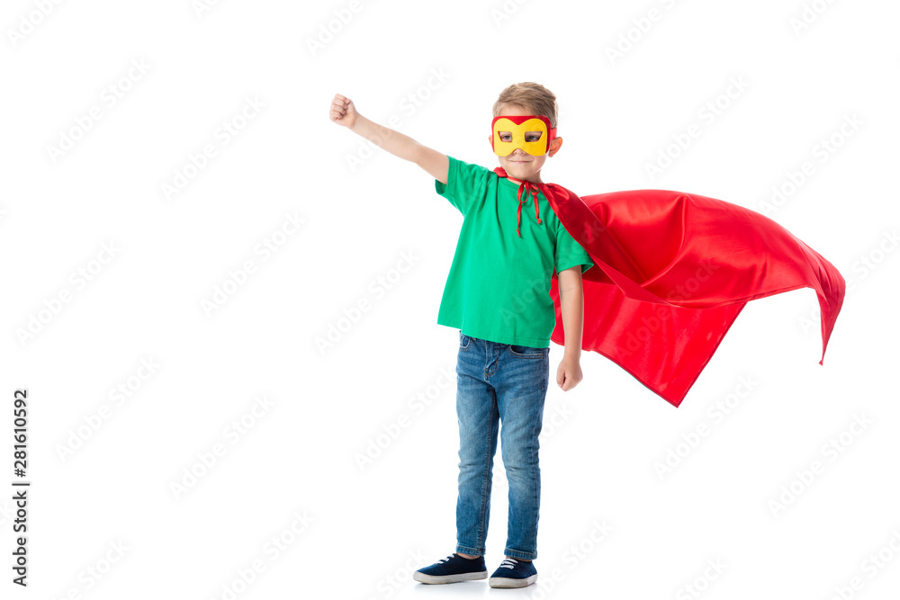 full length view of smiling preschooler boy in mask and red hero cloack standing with fist up isolated on white full length view of smiling preschooler boy in mask and red hero cloack standing with fist up isolated on white