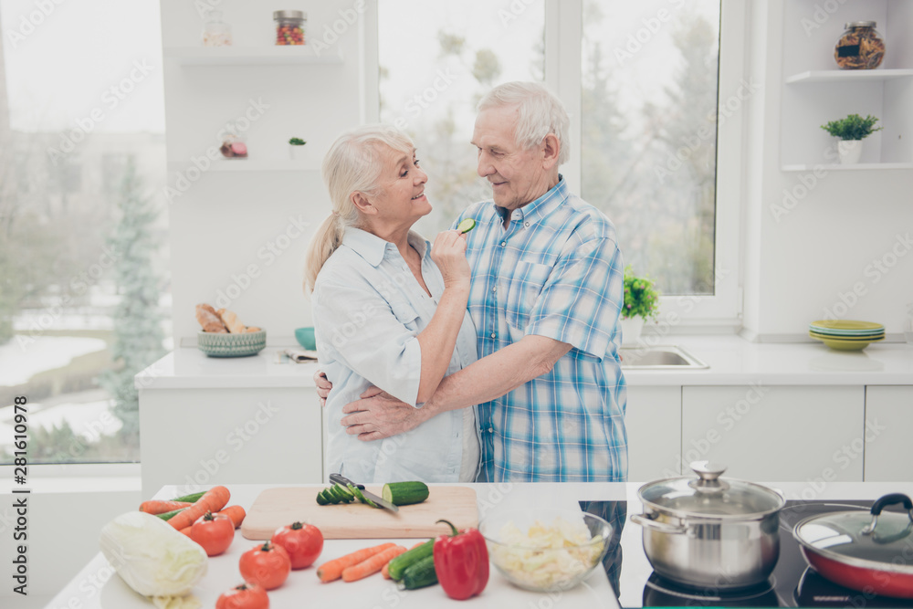 Close-up portrait of her she his he two nice attractive lovely cheerful cheery funny tender people having fun cooking together yummy dishes in modern light white interior kitchen indoors