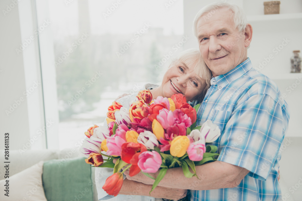 Closeup photo of two adorable aged people cute pair anniversary holiday surprise big red tulips bunch flat indoors - obrazy, fototapety, plakaty 