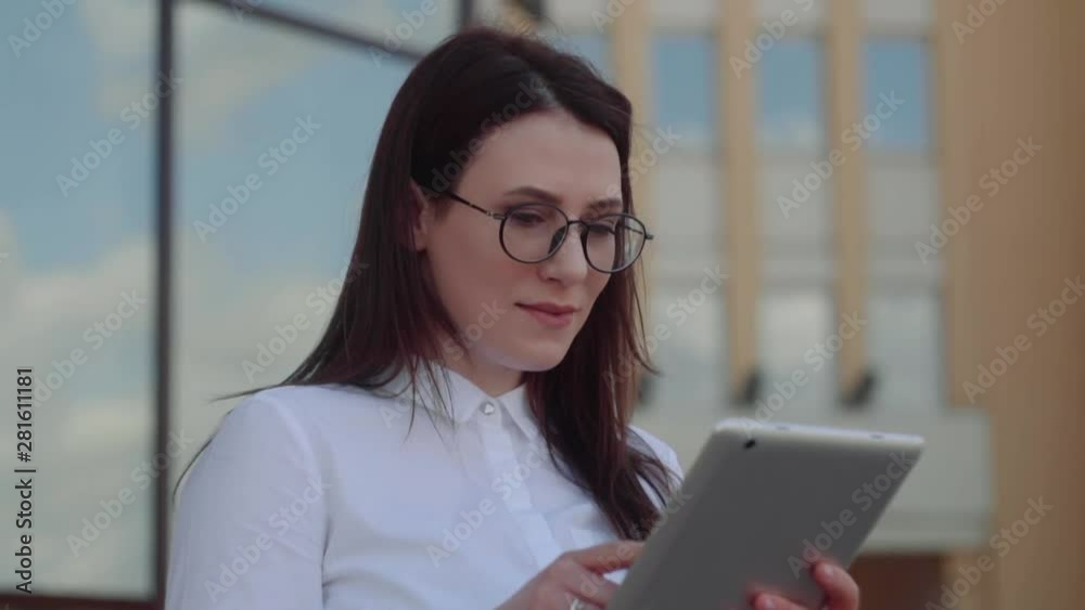 Portrait of smiling business woman using tablet pc in front of office building. Slow Motion Shot. Portrait of smiling business woman using tablet pc in front of office building. Slow Motion Shot.