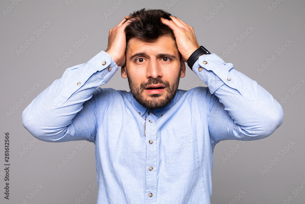 handsome man happy smile looking at camera, hold hands on head isolated on gray background.