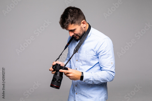 Young man take photo with dslr camera looking at camera isolated over gray abackground.