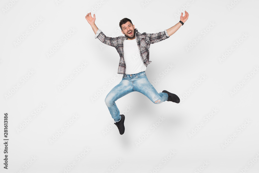 Happy man in shirt and jeans which jumping in studio over white background