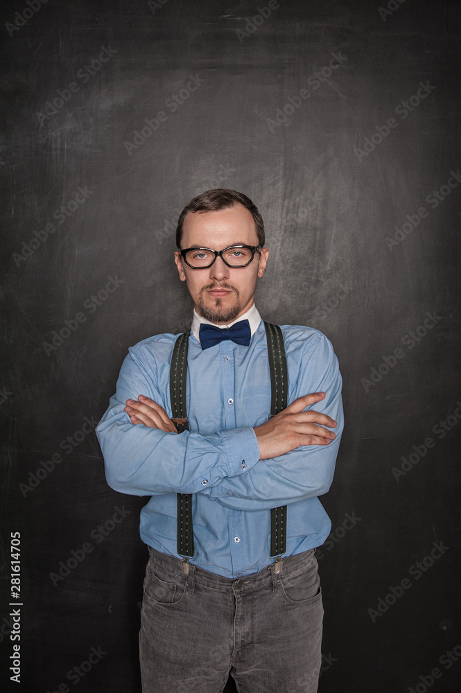 Handsome strict teacher in eyeglasses looking at you on blackboard