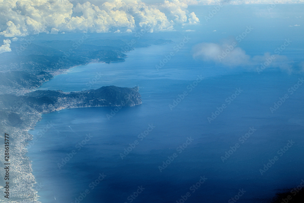 Italy from the plane: aerial view of the ligurian coast east from Genova with the waterfront surroundings of the city, the blue sea and the profile of the mount of Portofino