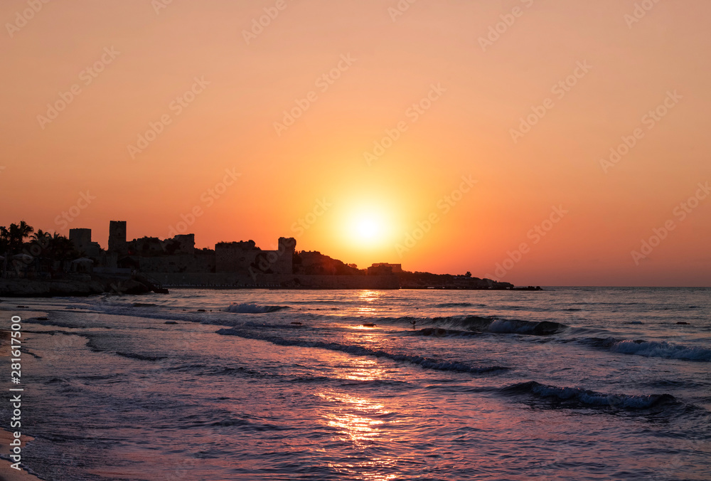 Beautiful golden sunrise over the sea and old fortress.