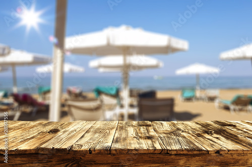 Fototapeta Naklejka Na Ścianę i Meble -  Table top background with a sunny sandy beach and sun beds and umbrellas. Empty space for advertising product and decoration.