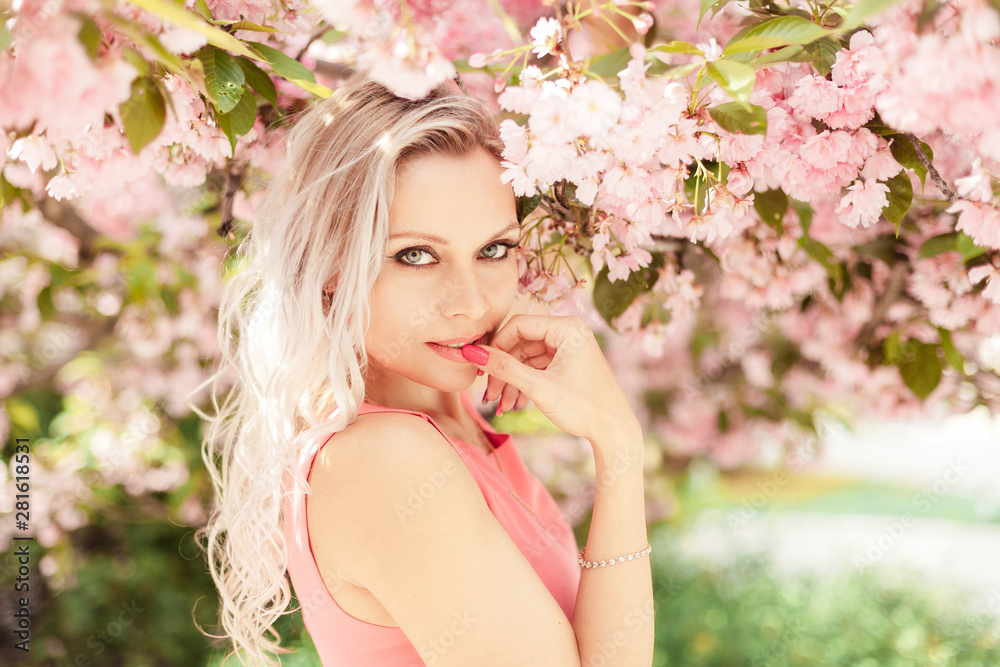  Beautiful blonde in a pink dress near a flowering tree
