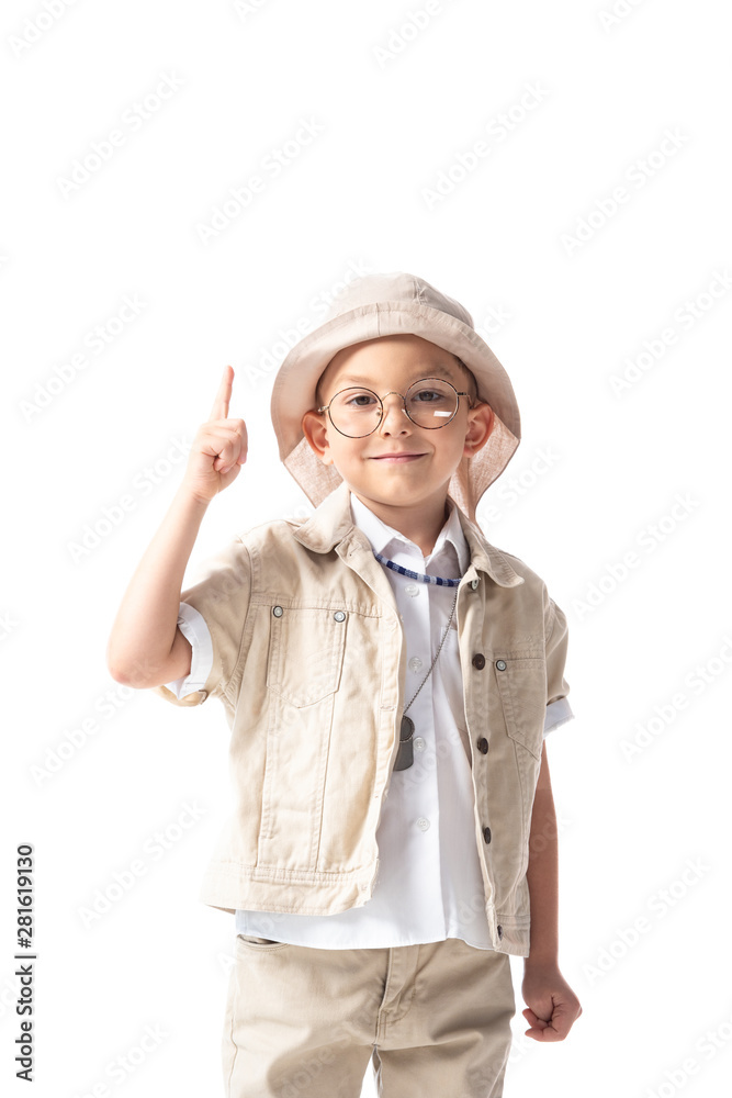 front view of smiling explorer boy in glasses and hat looking at camera and showing idea sign isolated on white front view of smiling explorer boy in glasses and hat looking at camera and showing idea sign isolated on white