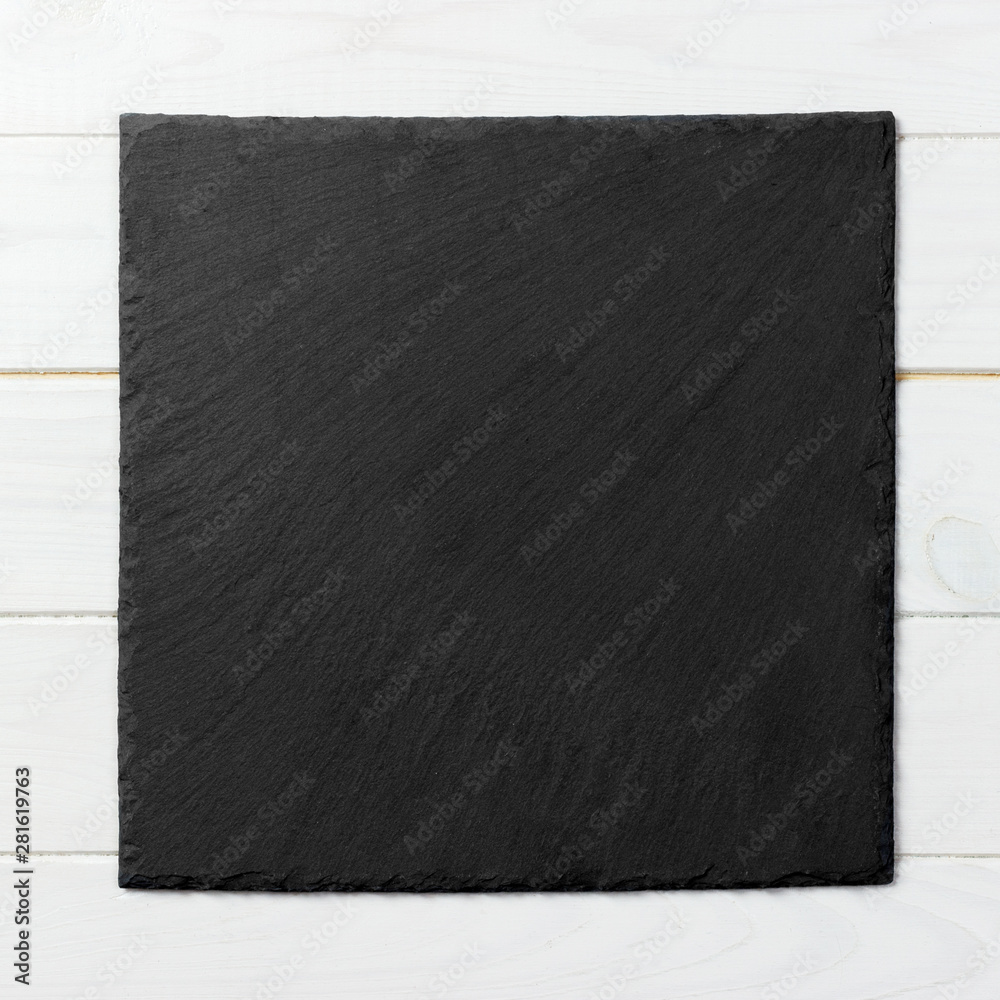 Black square plate on wooden background, top view, copy space