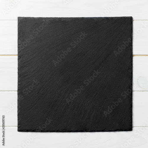 Black square plate on wooden background, top view, copy space