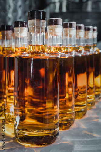 Small liquor production based on maple syrup. Multitude of pure alcohol bottles not labeled. Bottles placed in a row.