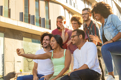 Cheerful happy interracial friends taking group selfie outside. Multiethnic men and women posing and laughing at phone camera. Friendship concept