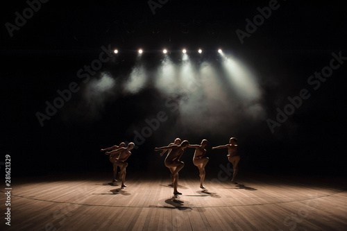 Valokuva A group of small ballet dancers rehearses on stage with light and smoke