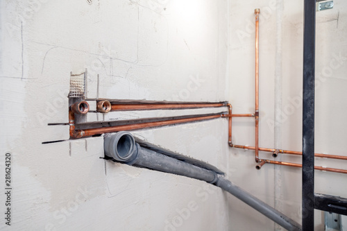 Closeup many new sewer copper and plastic pipes, fittings on concrete wall. Concept installation, replacement of plumbing, repair of pipeline, professional master plumber, leakage pipe