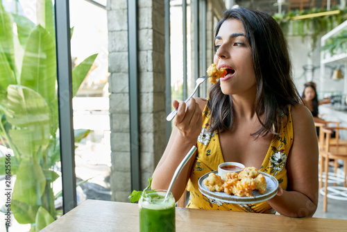 Fotografie Candid lifestyle portrait of fashionable healthy ethnic businesswoman eating an