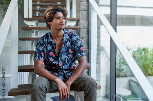 Free Download Attractive hispanic hipster millennial business man sitting on modern stairs of bright room with tropical plants - GFXLoad