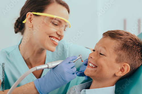 laughing little boy getting teeth treatment in dental clinic