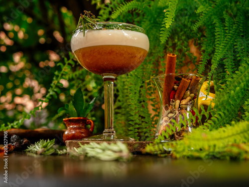 Brown cocktail in a glass goblet on a long leg. In the tropical garden. On a flat stone.