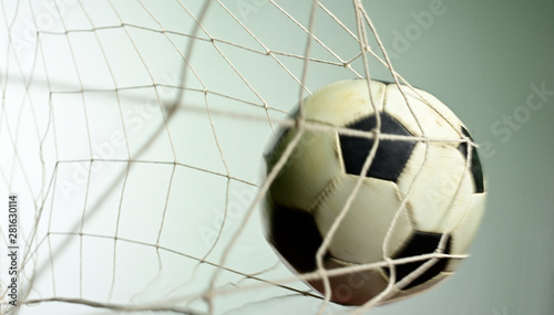 Scoring goal, Soccer ball in the net against gray background.