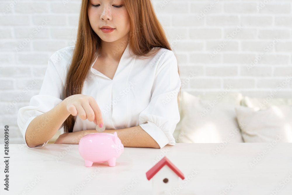 hand putting coin money to piggy bank saving, Close up of woman smiling putting a coin inside piggy bank as investment hand putting coin money to piggy bank saving, Close up of woman smiling putting a coin inside piggy bank as investment