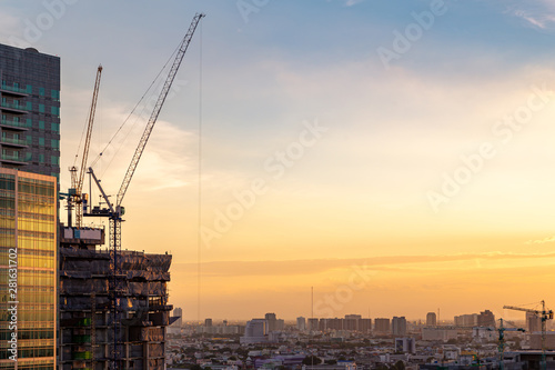 Construction site, Construction crane and modern city at sunset.