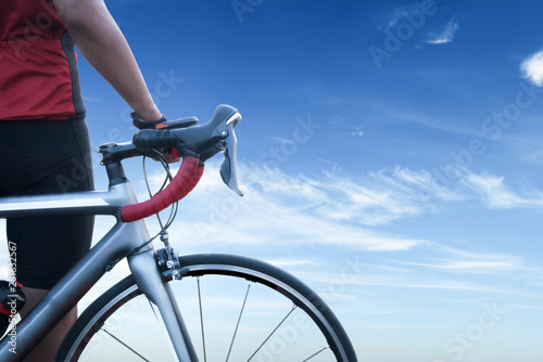 One cheerful cycling guy standing with his bike on blue sky background