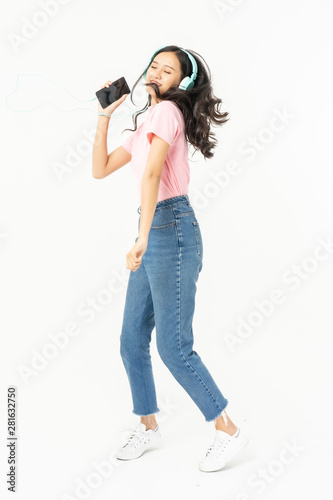 Happy asian teen passenger listening to the music with headphones while holding mobile phone.businesswoman listening to music with headphones while dancing isolated over white background
